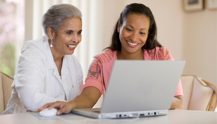 Two women looking at a laptop smiling