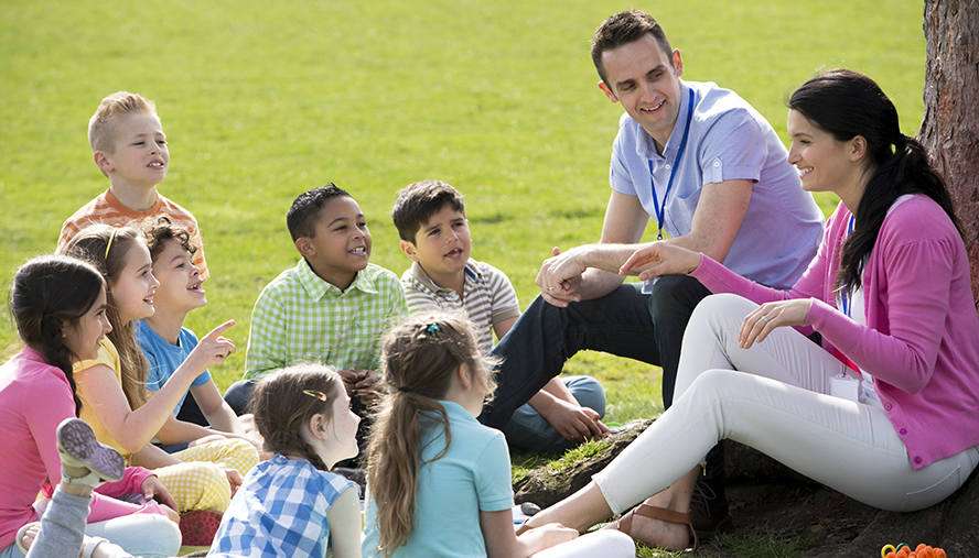 Group of children sitting in front of two camp counselors.