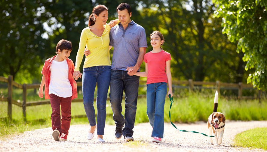 Adult couple taking a walk outside with two children and a dog.
