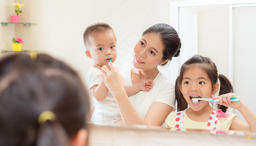 Parent and children brushing teeth before bed.