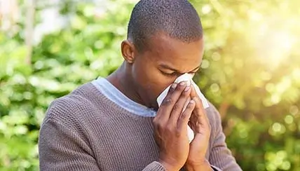 Man suffering from allergies blowing his nose