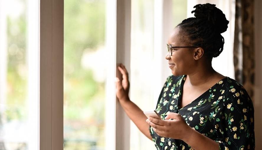 Woman staring out the window, phone in hand